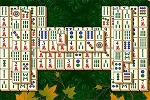 Pöydälle asetettuja mahjong-laattoja vihreällä taustalla, jossa on syksyn lehtiä
