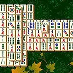 Pöydälle asetettuja mahjong-laattoja vihreällä taustalla, jossa on syksyn lehtiä