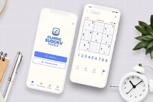 Kaksi älypuhelinta, joista toisessa on sudoku-käynnistysnäyttö ja toisessa sudokupeli avattuna, pöydällä, jossa on kynä, muistikirja ja herätyskello