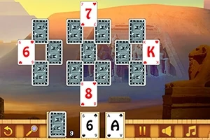 Pasianssikortit järjestettynä pyramidimuodostelmaan, taustalla aavikkomaisema sfinksin kanssa