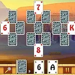 Pasianssikortit järjestettynä pyramidimuodostelmaan, taustalla aavikkomaisema sfinksin kanssa