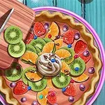 Värikäs hedelmäpiirakka, jossa on kiiviä, appelsiinia, mansikoita, kermavaahtoa ja koristehelmiä, puiseen leikkuulautaan nojaavan veitsen vieressä