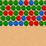 Punaisia, sinisiä ja vihreitä palloja rivissä hiekanvärisellä taustalla