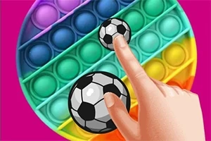 Kuva esittää kättä painamassa jalkapallo-kuviollisia pop it -kuplia sateenkaaren värisessä pyöreässä lelussa