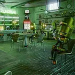 Robottien täyttämä ravintola, jossa on vihreä valaistus ja baari, jonka yläpuolella on Le Robobar -kyltti