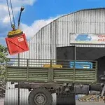 Kuorma-auto seisoo varaston edessä, ja nosturi laskee punaista konttia sen viereen